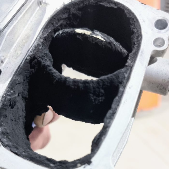 En insugsdel av en motor fylld med sot innan rengöring